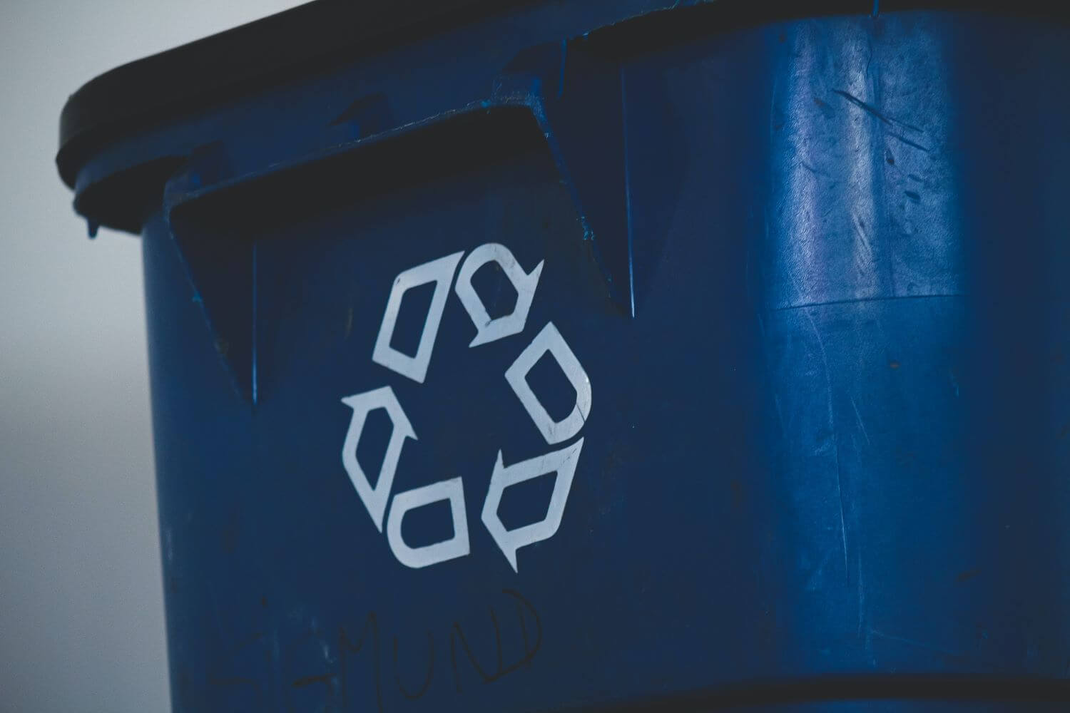 Un contenedor azul con el signo de reciclaje